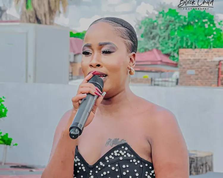 Nthabi speaking into the microphone at an outdoor event