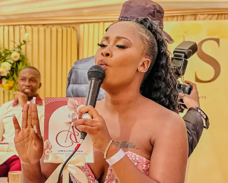 Nthabi mid-speech at a wedding, hand raised